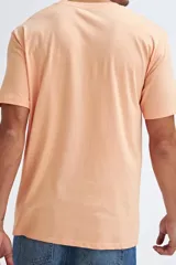 Camiseta de manga corta color salmón con estampado frontal estilo retro con temática de surf.