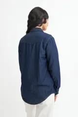 Camisa de denim azul con dos bolsillos frontales con botón, corte recto y mangas largas con puños abotonados.
