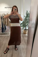 Vestido largo tejido color marrón con rayas horizontales beige y blancas en la parte superior, detalle calado en la parte inferior y tajos a los costados.