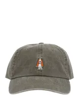 Gorra de estilo clásico con efecto lavado, confeccionada en algodón orgánico. Presenta un bordado frontal de un perro basset hound y cuenta con ajuste mediante hebilla metálica en la parte posterior.