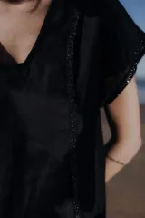 Túnica negra con escote en V y mangas cortas con detalle de lentejuelas en los bordes.