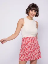 Falda corta con estampado de flores en tonos rojos, rosados y blancos, con cierre lateral.