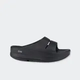 Sandalias de plataforma Oofos modelo Oomega, color negro, con diseño tipo slide y tecnología OOfoam para mayor amortiguación.