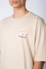 Remera blanca de corte oversize con mangas cortas y cuello redondo. Estampado pequeño en el frente con letras verdes.