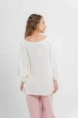 Sweater oversize de tejido liviano color blanco roto, con textura semi traslúcida, escote redondo y mangas amplias estilo murciélago.