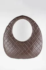 Cartera de cuero color marrón, con silueta ovalada, diseño capitoné de rombos y asa circular integrada. Cuenta con detalles metálicos dorados con el logo de la marca.