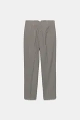 Pantalón tobillero de tiro alto con estampado de cuadros pequeños en tonos beige y negro. Presenta costuras marcadas en el delantero y la espalda, bolsillos laterales de vivo y cierre frontal con cremallera, botón interior y gancho metálico.