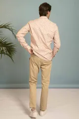 Camisa de manga larga en color salmón con estampado de pequeños motivos geométricos oscuros, cuello clásico y cierre frontal con botones.