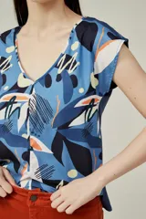 Blusa de poliéster sin mangas, con cuello en V y estampado abstracto multicolor en tonos beige, marrón, negro y naranja.