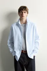 Camisa slim fit de algodón color celeste con sutil patrón de cuadros, cuello clásico y manga larga con puños abotonados.