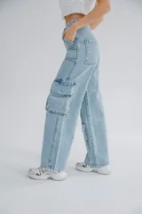 Pantalón jean celeste de tiro alto, corte recto y estilo cargo, con bolsillos laterales con solapa y cierre con cremallera en los tobillos.