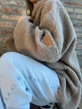 Campera de corderito color verde oscuro, con diseño holgado, cuello alto y manga larga. Presenta una etiqueta de cuero sintético en la manga.