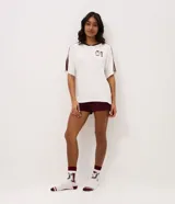 Pijama corto de dos piezas confeccionado en viscolycra. Incluye remera blanca de manga corta con cuello en V bordó, rayas en los hombros y estampa de Winnie The Pooh con el número 01 en el pecho, y short corto color bordó con cintura elastizada.