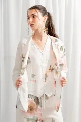 Blazer de lino con estampado floral en tonos rosados y verdes, cuello con solapa, bolsillos laterales y cierre frontal con un botón.