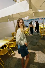 Cazadora de cuello redondo y manga larga, color verde claro con patrón a cuadros. Confeccionada en tejido de organza con estructura y acabados elásticos. Cierre frontal con cremallera y bolsillos delanteros.