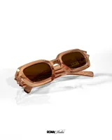 Lentes de sol con armazón rectangular de acetato en color rosa traslúcido y cristales oscuros con protección UV 400.