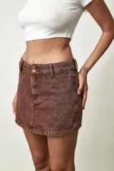 Short pollera de jean de tiro medio, color azul claro, con doble botón en la cintura y diseño de falda corta al frente con pantalón corto interno.