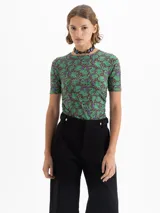 Top de punto color verde con estampado de dragones en tonos marrones y violetas. Tiene escote redondo, mangas cortas y frunces laterales que realzan la silueta.