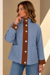 Campera confeccionada en lino, de silueta amplia y color celeste con detalles en marrón tostado en la botonera y los puños. Presenta cuello alto, bolsillos frontales aplicados, forrería interior y botones de nácar.