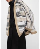 Cardigan tipo kimono confeccionado en punto jacquard con diseño de rayas irregulares en blanco, negro y beige, con mangas japonesas, aberturas laterales y remates en contraste.