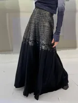 Falda larga plisada color marrón con estampado geométrico dorado en la parte superior y bolsillos laterales.