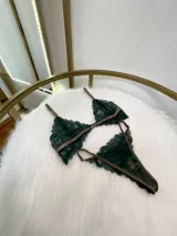 Conjunto de lencería compuesto por un bralette de encaje verde esmeralda con cierre frontal y una tanga a juego con tiras regulables, ambos con detalles de ribetes en color marrón.