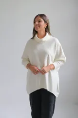 Polerón de punto color crudo, con cuello alto tipo polera, corte holgado y mangas largas con puños acanalados.