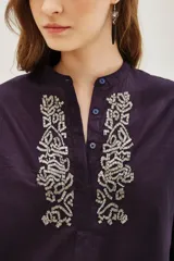 Camisa de algodón color blanco, con cuello redondo, cierre frontal parcial con botones y detalle de bordado con canutillos en el frente.