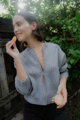 Campera de punto color beige, con cierre frontal, cuello alto y diseño de líneas verticales. Incluye una bufanda a juego del mismo tejido.