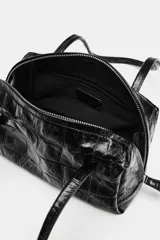 Bolso de hombro negro de formato bowling con textura efecto cocodrilo, doble asa de hombro y cierre con cremallera.
