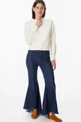 Saco tipo cardigan de punto color crudo, con cuello redondo, cierre frontal de botones y mangas largas con puños acanalados.