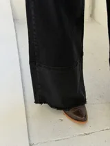 Pantalón de jean negro de corte wide leg con diseño de costura horizontal en el ruedo y terminación deshilachada. Cuenta con cierre frontal y bolsillos laterales.