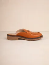 Mocasín abierto color caramelo, estilo mule, con taco bajo y detalle de cadena dorada en la capellada.