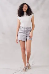 Top sin mangas, cuello tortuga, color blanco con acabado brillante o metálico. Tejido acanalado y ajustado al cuerpo.