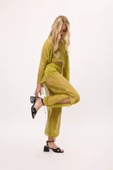 Pantalón ancho de seda color amarillo, estilo parachute o globo, con talle alto y cordones ajustables en los tobillos.