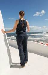 Top sin mangas de lino, con cuello redondo y cierre posterior mediante tres lazos. Diseño minimalista y versátil.