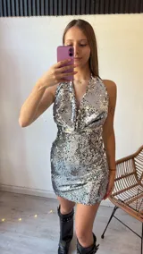 Minivestido plateado con lentejuelas, escote halter y espalda descubierta.