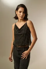 Musculosa negra de poliéster con cuello buche, breteles finos y apliques de tachas metálicas en toda la parte frontal.