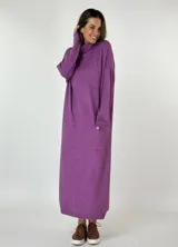 Vestido largo de punto color lavanda, con cuello tortuga, mangas largas y bolsillos laterales con detalle de botón dorado.