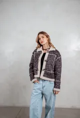 Campera de gamuza con estampado animal print en tonos grises, forrada con corderito sintético en color crema. Presenta cierre frontal con botones tipo toggle y detalles de costuras visibles.