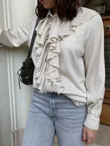 Camisa color crema de lana tejida con cuello camisero y volados frontales.