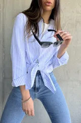 Camisa de manga larga con rayas verticales celestes y blancas, de corte recto y largo con aberturas laterales.