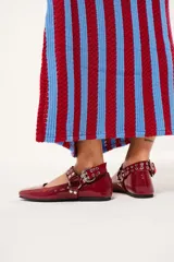 Balerinas color borgoña de charol con punta cuadrada, correa con hebilla y apliques metálicos.