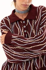 Buzo de punto color vino con diseño de rayas verticales irregulares en tonos claros. Presenta cuello polo con cierre frontal de tres botones, mangas largas con puños acanalados y corte holgado.
