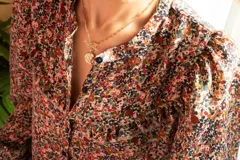 Camisa de gasa estampada con flores, corte clásico, cuello redondo, mangas largas abuchonadas y cierre frontal con botones.