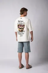 Remera de corte oversize color gris oscuro, confeccionada en algodón premium de alto gramaje. Presenta un diseño minimalista con un pequeño estampado frontal que incluye un oso y el texto 'Richer & Louder VCP'.