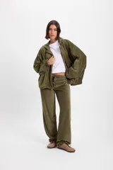 Pantalon de tiro bajo con diseño híbrido que combina elementos formales y deportivos. Presenta cintura y bajos ajustables, con elástico en la parte trasera de la pretina interna.