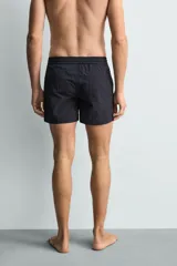 Short de baño de color azul marino, confeccionado en tejido técnico, con cintura elástica ajustable mediante cordón, bolsillos laterales y detalle de bolsillo trasero.