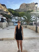 Vestido corto negro con escote halter y cierre frontal con cremallera dorada.