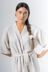 Bata kimono corta color beige, confeccionada en tela waffle de algodón. Tiene mangas al codo, lazo de ajuste en la cintura y detalle de vivo en la solapa.